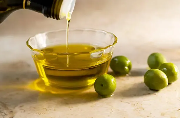 Extra virgin olive oil being poured, highlighting healthy monounsaturated fats for liver health
